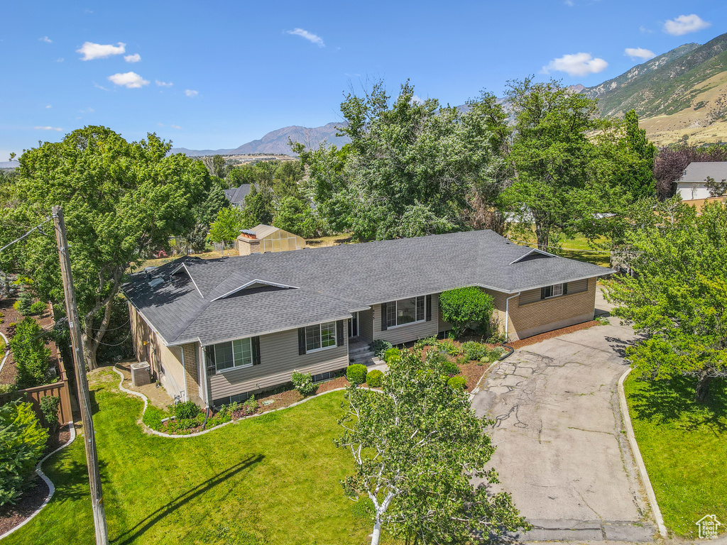 View of front of property with roof with shingles, a mountain view, driveway, and a front lawn