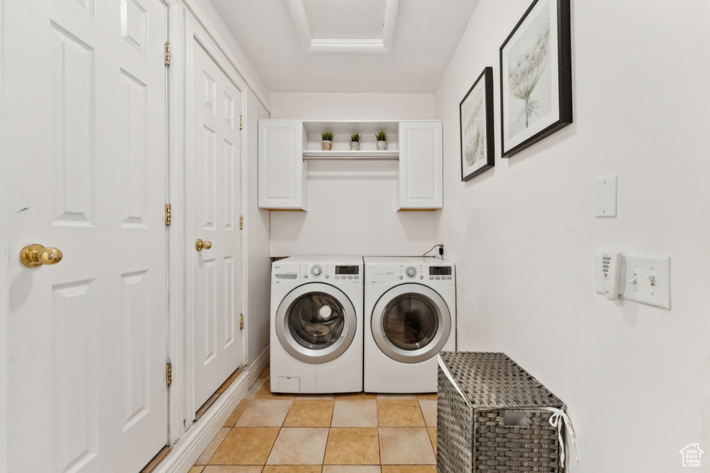 Laundry area featuring cabinet space, washing machine and dryer, and light tile patterned floors