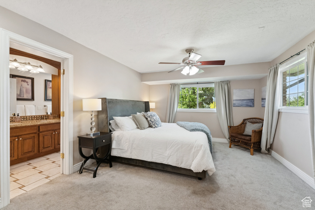 Bedroom featuring light carpet, connected bathroom, ceiling fan, and a textured ceiling
