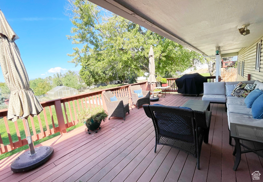 Wooden deck with outdoor lounge area, grilling area, a greenhouse, and an outdoor structure