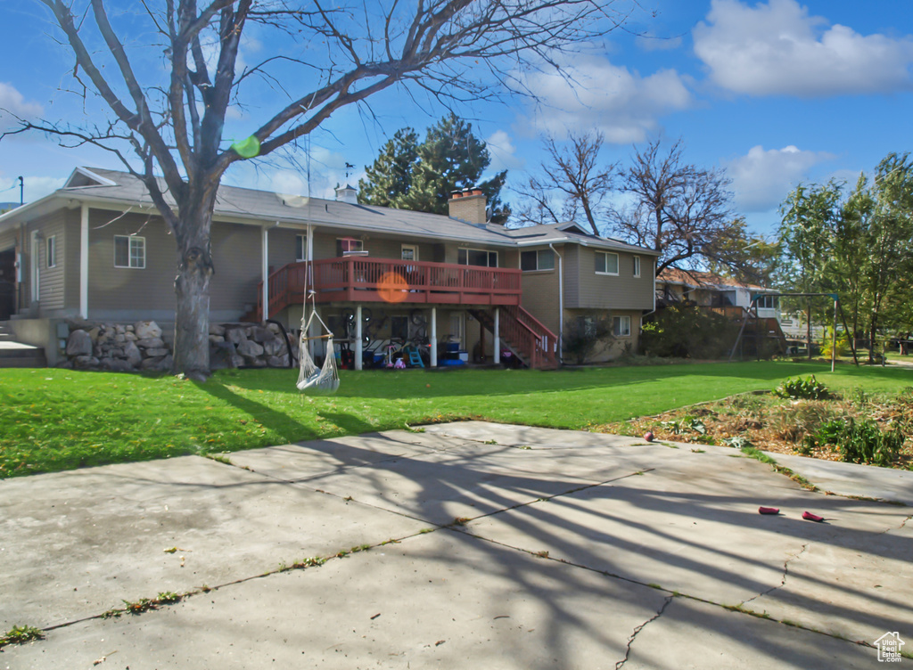 Back of property with a chimney, a wooden deck, stairs, a yard, and a patio
