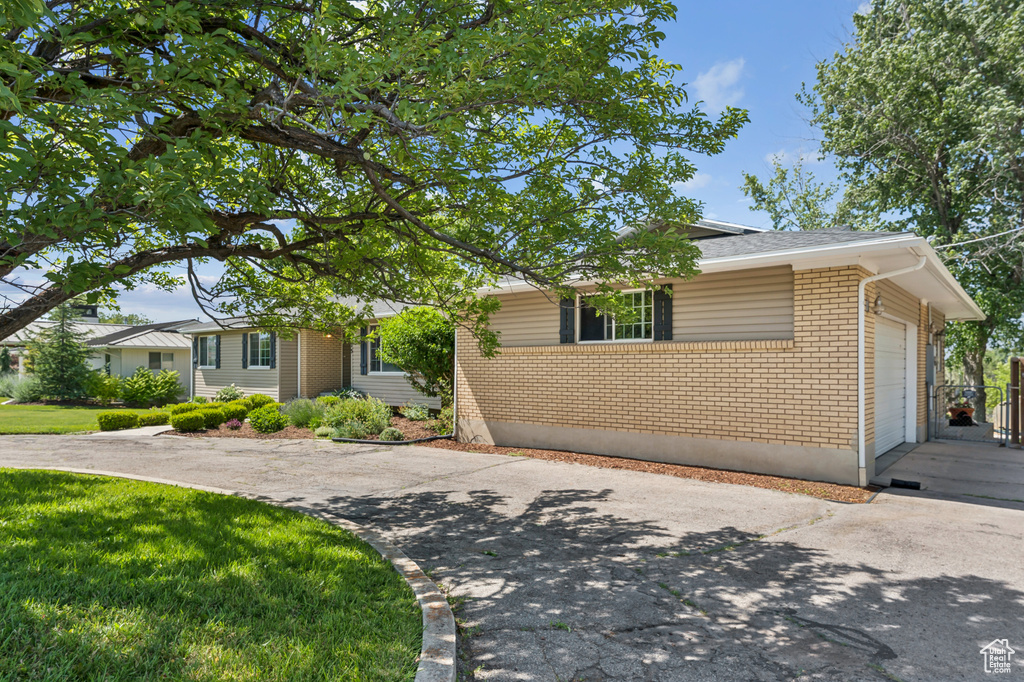 View of front of property featuring brick siding, an attached garage, concrete driveway, and a front yard