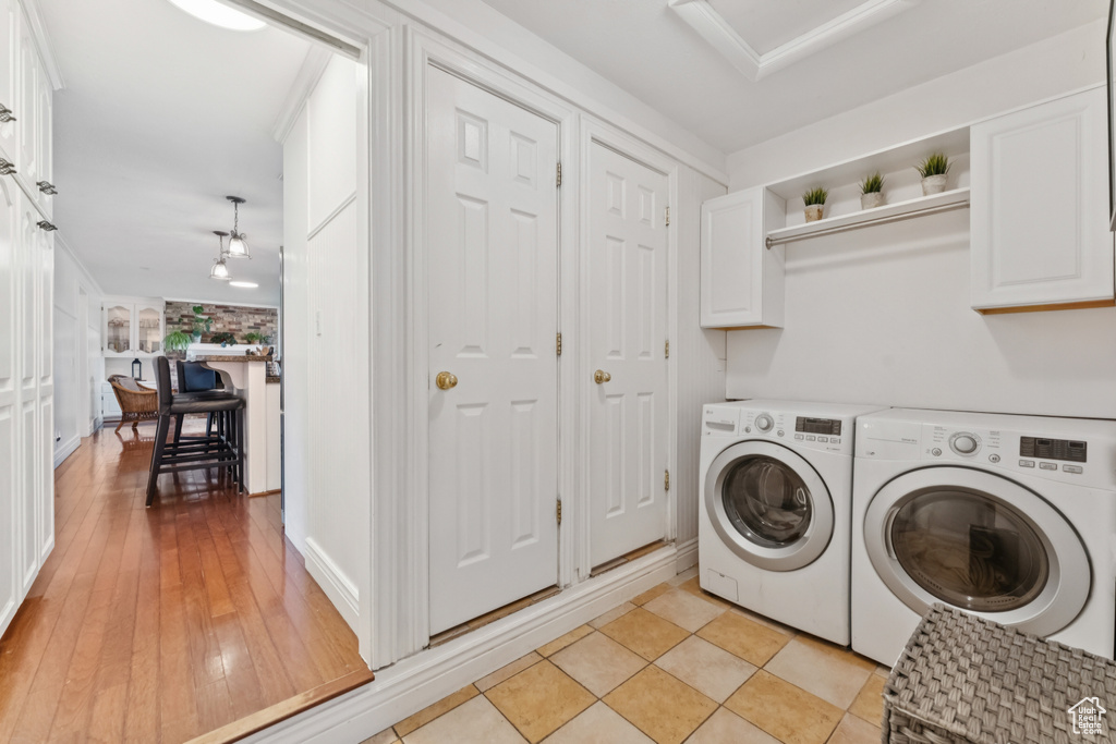 Washroom featuring cabinet space, washer and clothes dryer, attic access, and light wood finished floors