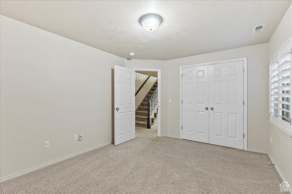Unfurnished bedroom with light colored carpet, a closet, and baseboards