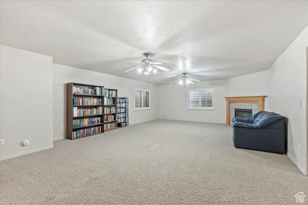 Unfurnished room with a ceiling fan, carpet flooring, a fireplace, and baseboards