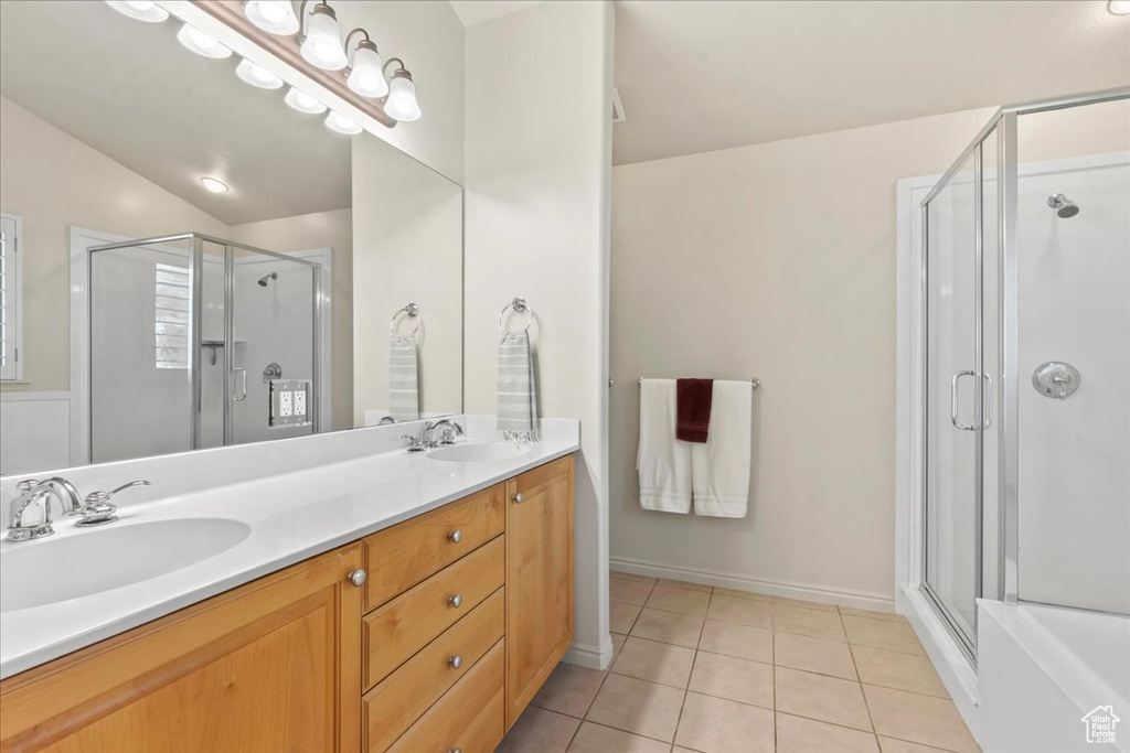 Bathroom with tile patterned floors, a stall shower, and double vanity