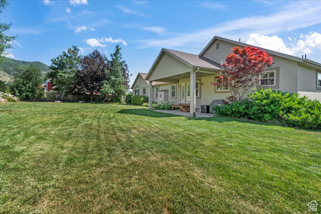 View of grassy yard featuring a patio area