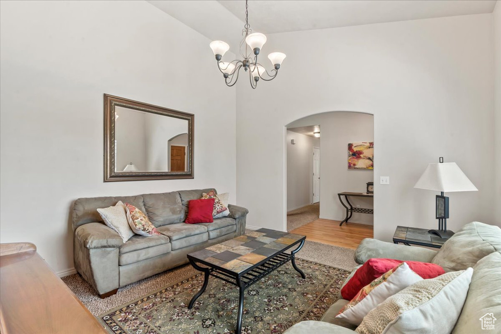 Living room featuring arched walkways, a chandelier, wood finished floors, and a towering ceiling