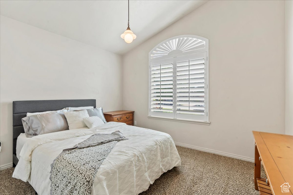 Carpeted bedroom featuring vaulted ceiling and baseboards