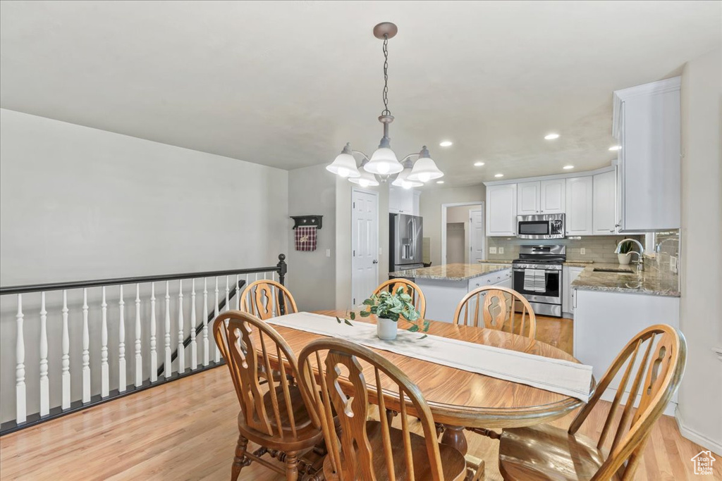 Dining space with a chandelier, light wood finished floors, recessed lighting, and baseboards