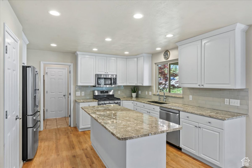 Kitchen with stainless steel appliances, a sink, white cabinets, decorative backsplash, and recessed lighting