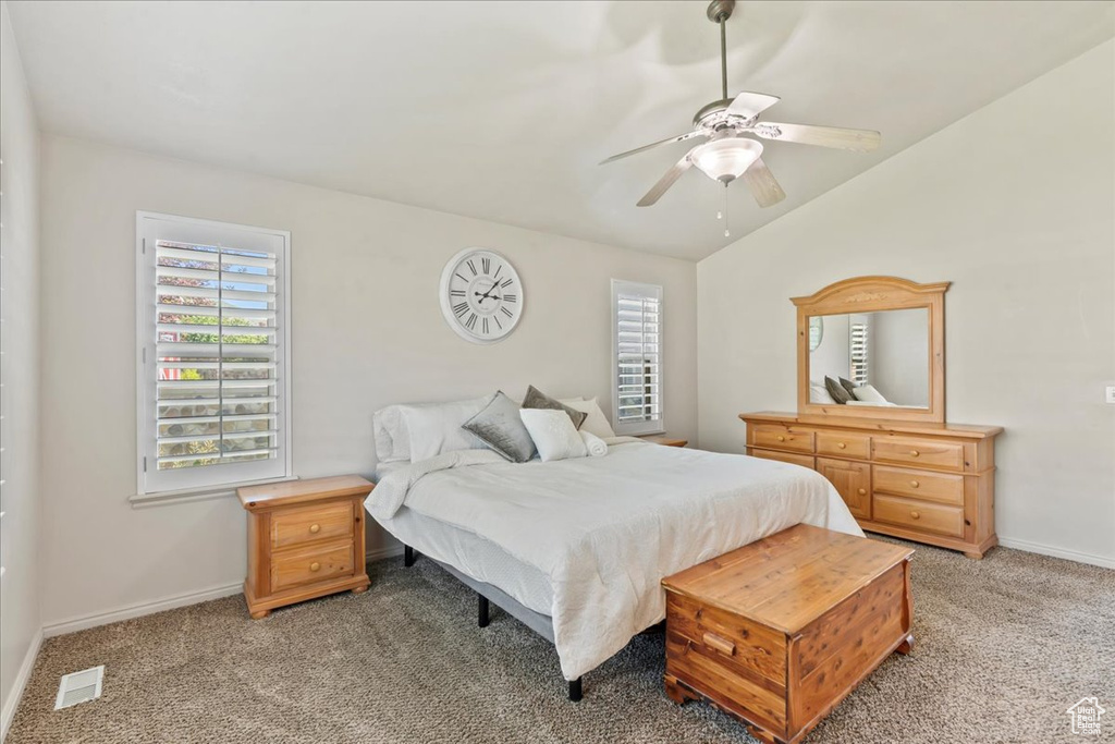 Bedroom with multiple windows, light carpet, vaulted ceiling, and baseboards