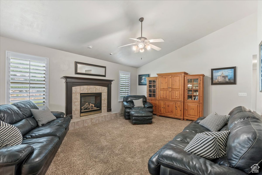 Living room featuring carpet floors, ceiling fan, vaulted ceiling, and a fireplace