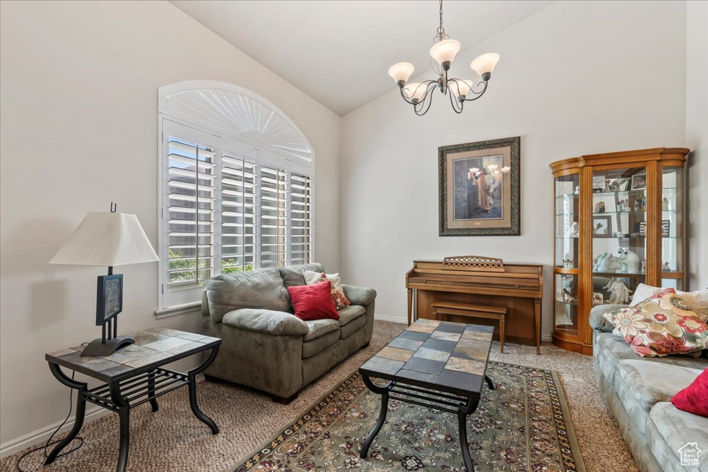 Living room featuring a chandelier, carpet flooring, high vaulted ceiling, and baseboards