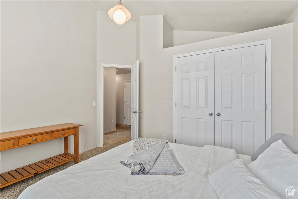 Bedroom with carpet flooring, baseboards, a closet, and high vaulted ceiling