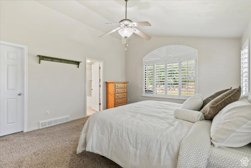 Carpeted bedroom with connected bathroom, baseboards, and ceiling fan