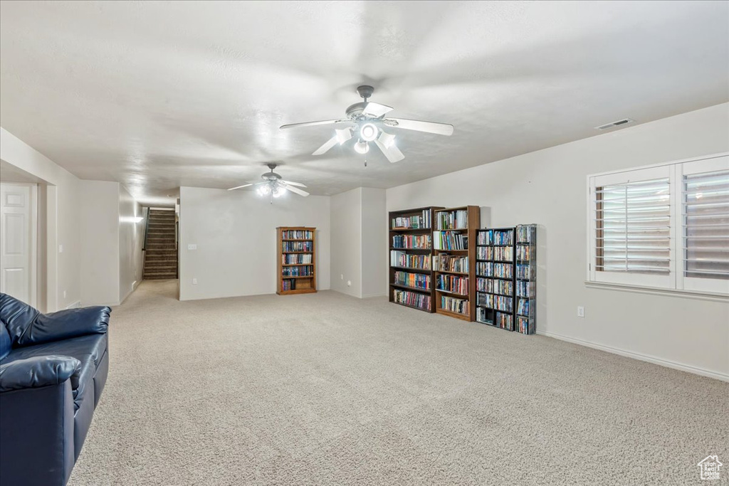 Living area featuring stairway, carpet, and ceiling fan