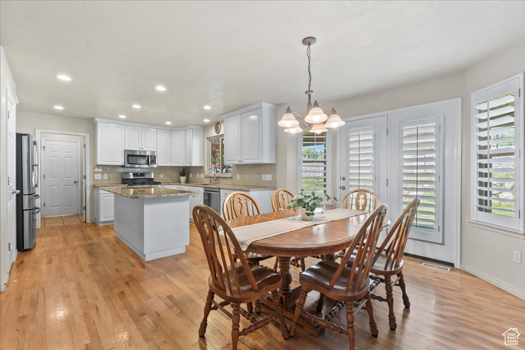 Dining space featuring healthy amount of natural light, a chandelier, light wood-type flooring, recessed lighting, and baseboards