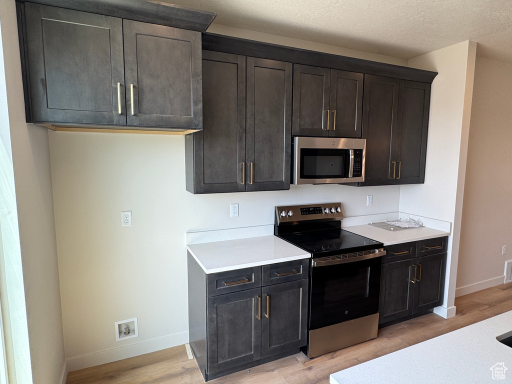 Kitchen featuring stainless steel appliances, light wood-style floors, light countertops, and a textured ceiling