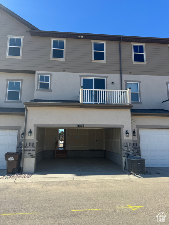 Back of property featuring an attached garage, central AC unit, and stucco siding