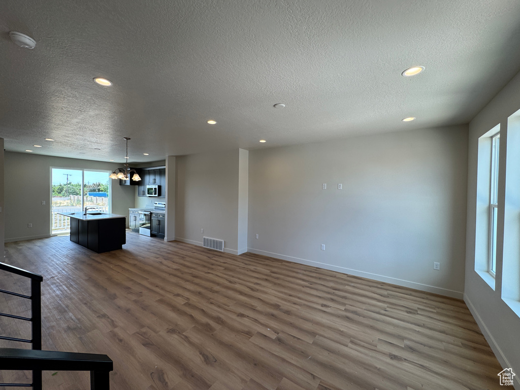 Unfurnished living room featuring a textured ceiling, wood finished floors, and recessed lighting