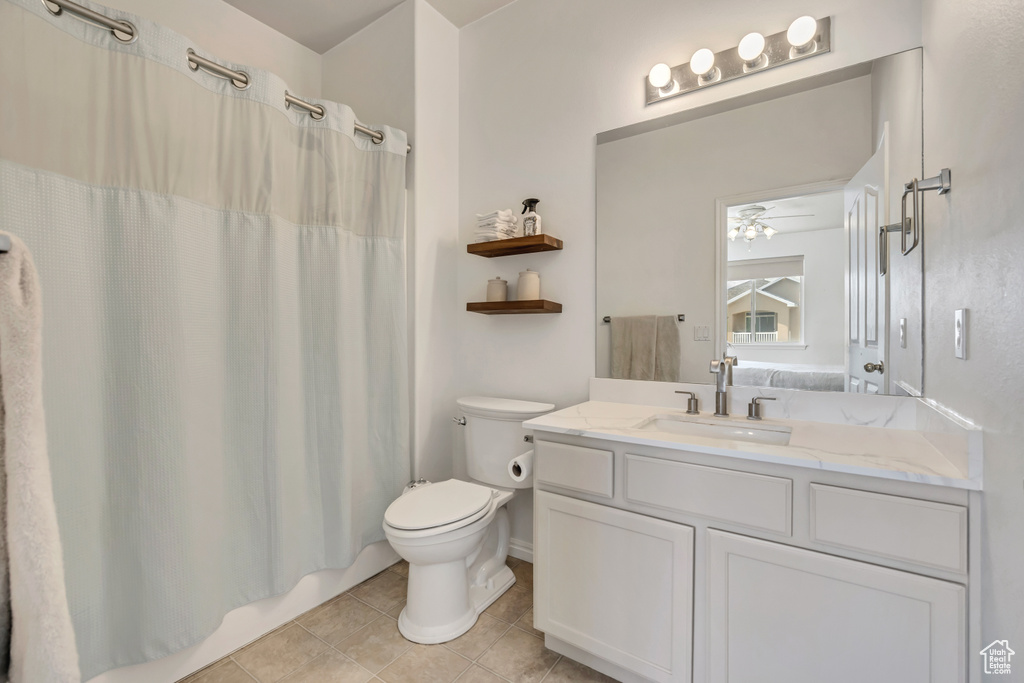Bathroom featuring vanity, tile patterned flooring, toilet, ceiling fan, and curtained shower