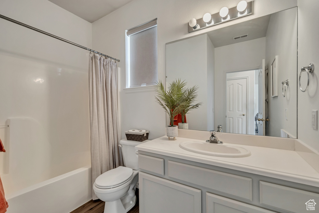 Full bath featuring vanity, toilet, shower / tub combo with curtain, and wood finished floors