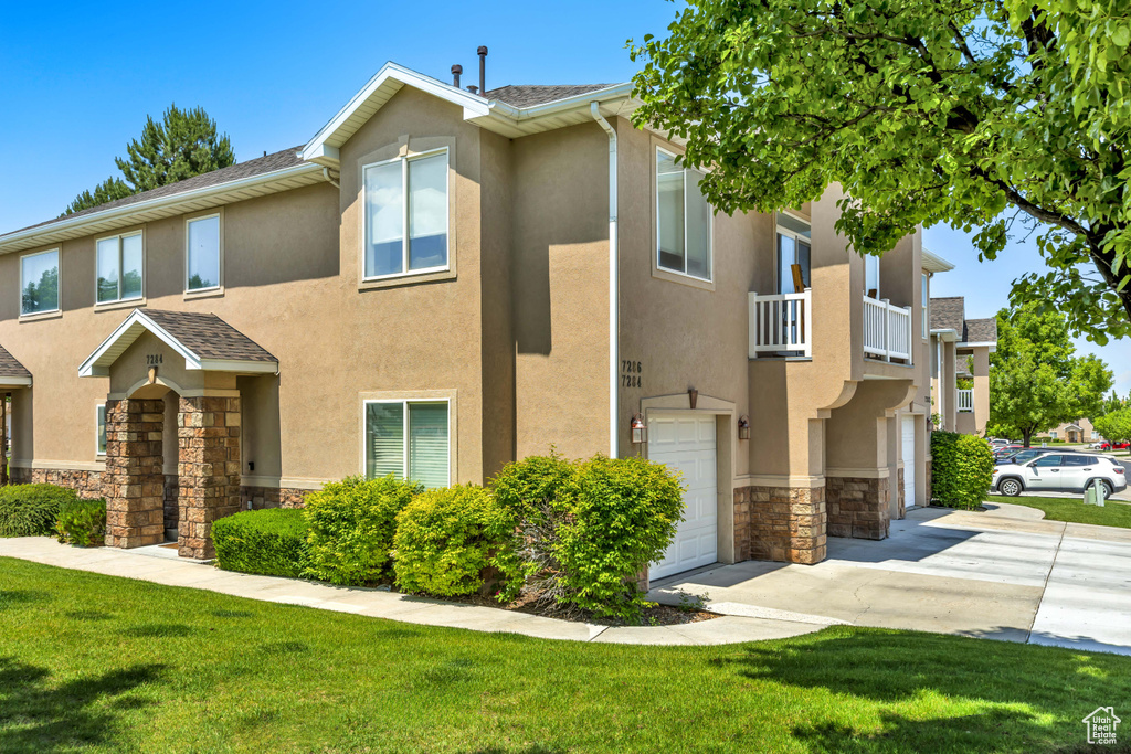 Townhome / multi-family property featuring stone siding, stucco siding, a garage, and driveway