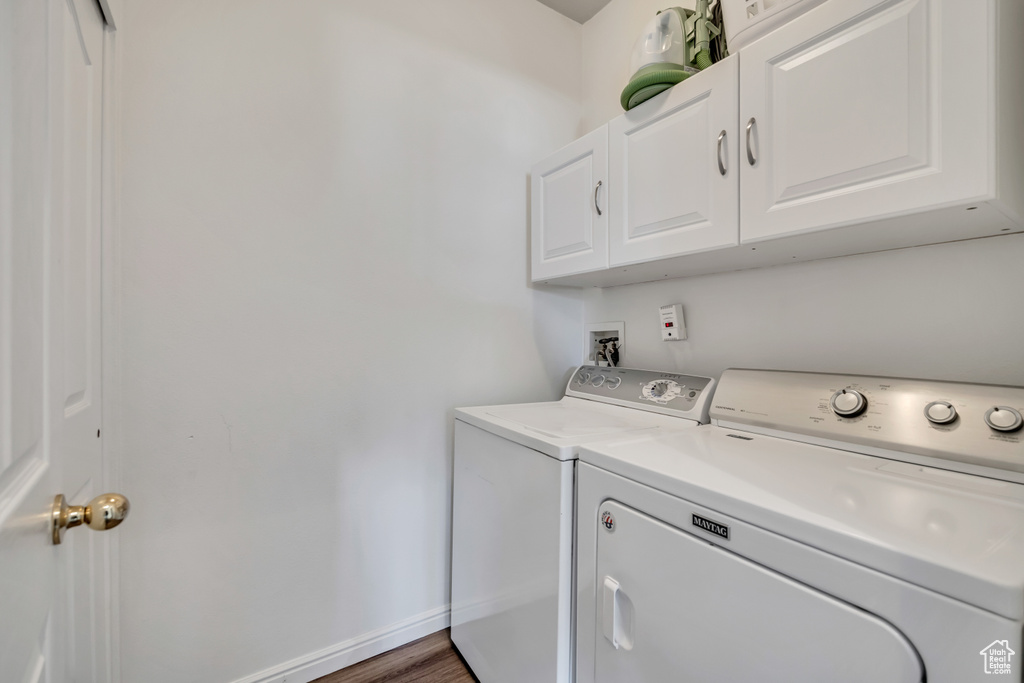 Washroom featuring cabinet space, washer and dryer, and wood finished floors