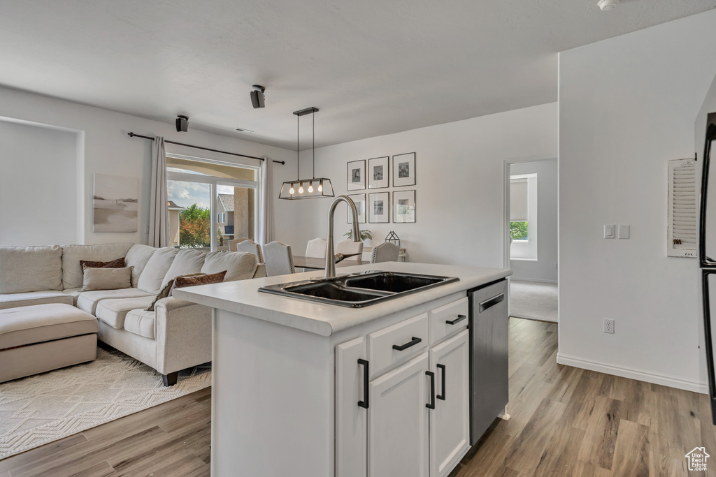 Kitchen with a sink, white cabinets, light wood finished floors, and dishwasher