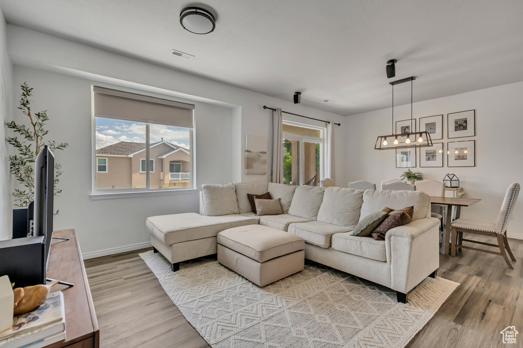 Living room with a chandelier, wood finished floors, and healthy amount of natural light