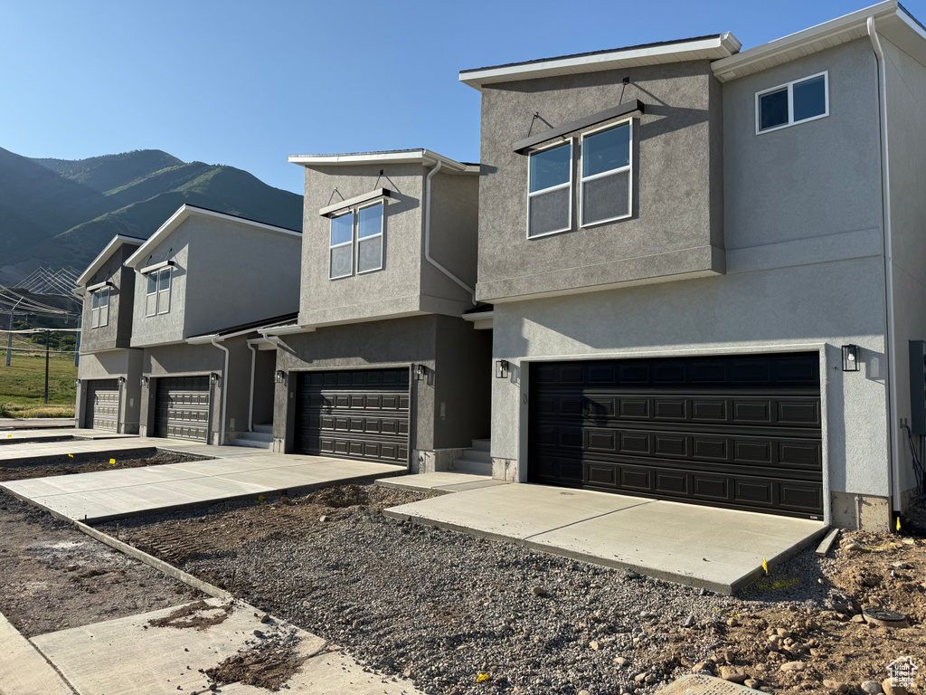 View of front of property featuring a garage, stucco siding, and a mountain view