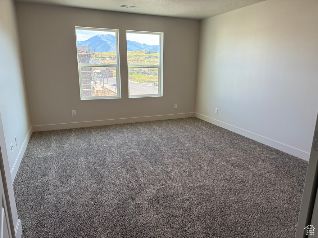 Unfurnished room featuring carpet, baseboards, and a mountain view