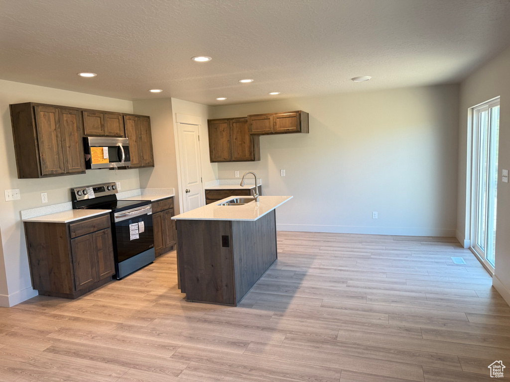 Kitchen with stainless steel appliances, a sink, baseboards, recessed lighting, and light countertops