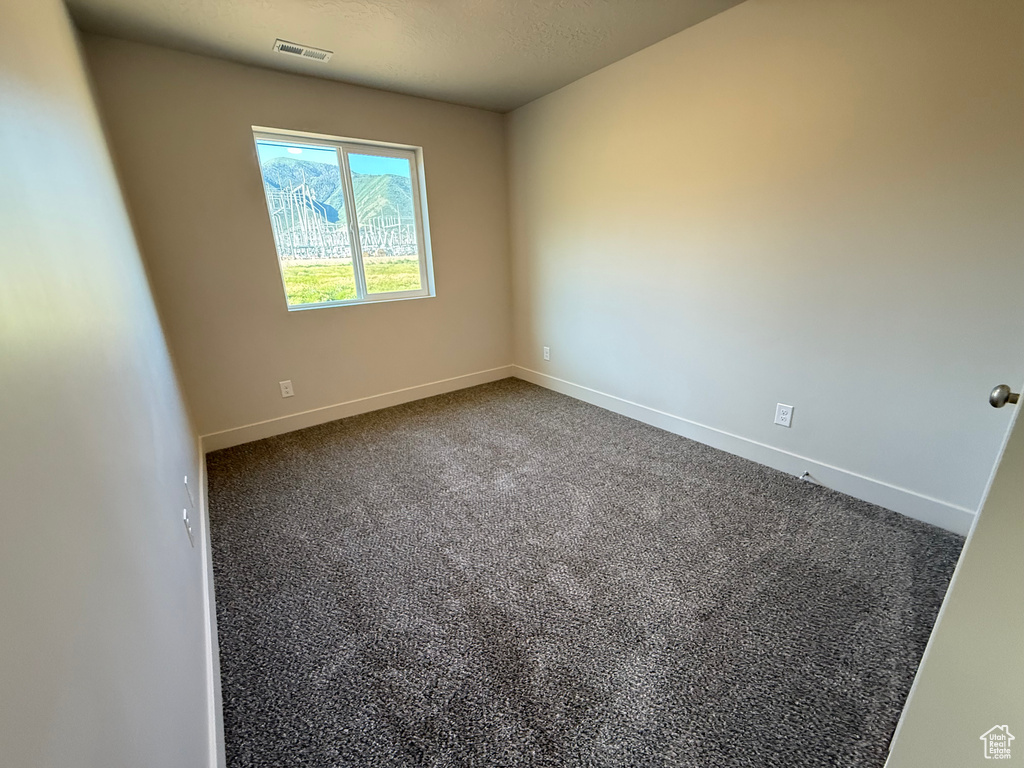Unfurnished room with baseboards and dark carpet