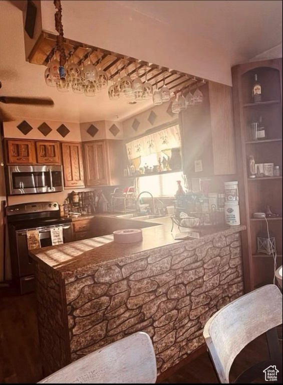 Bar with stainless steel microwave, electric range, a sink, and dark wood-style flooring