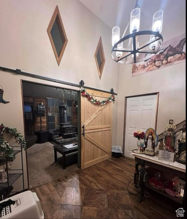 Entrance foyer with dark wood-type flooring, high vaulted ceiling, a chandelier, and a barn door