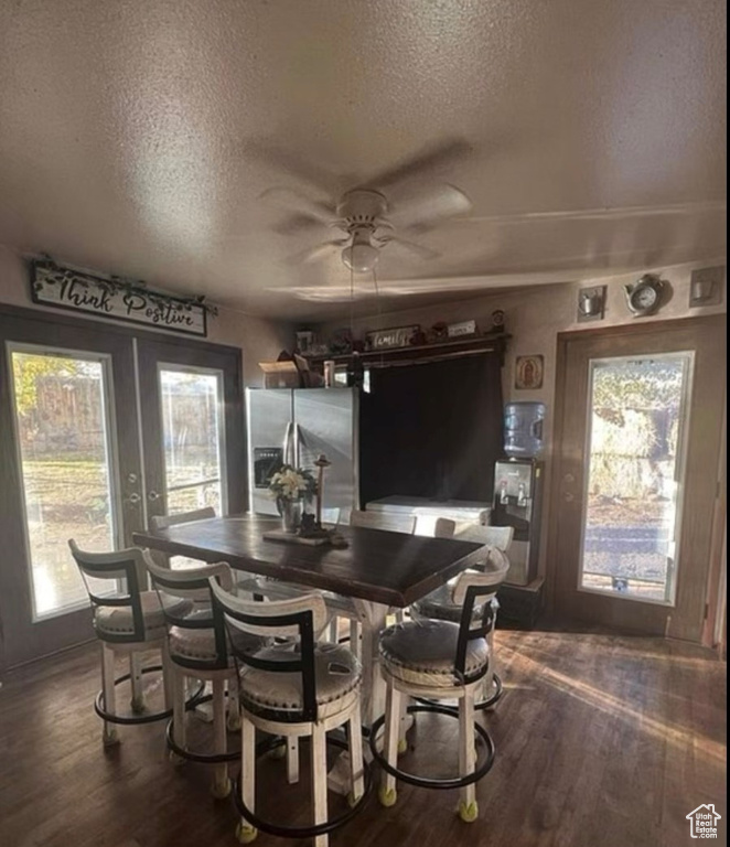 Dining room with a textured ceiling, a ceiling fan, dark wood-style floors, and french doors