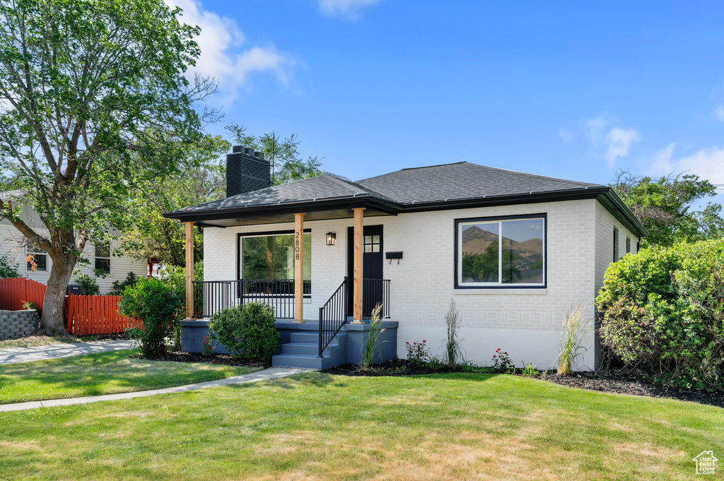 Bungalow with brick siding, a porch, a chimney, and a shingled roof