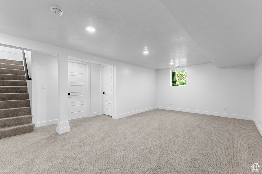Below grade area with baseboards, light carpet, stairs, and recessed lighting