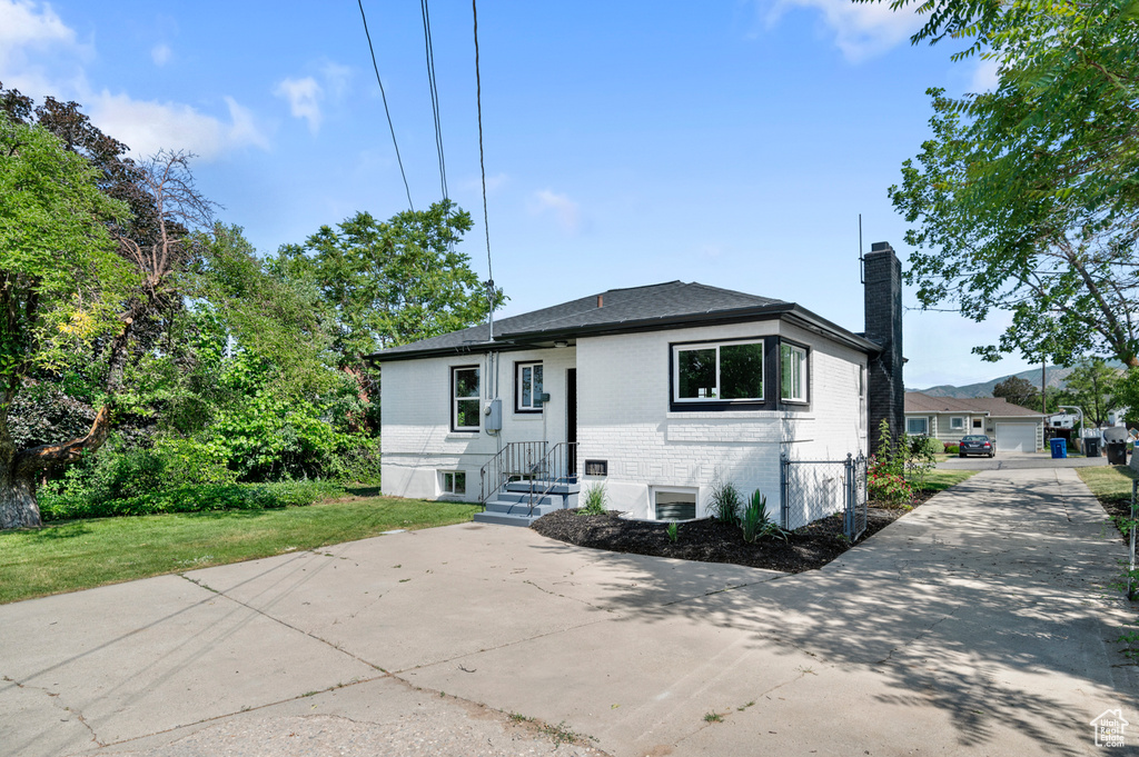 View of front of home with brick siding, a chimney, and concrete driveway