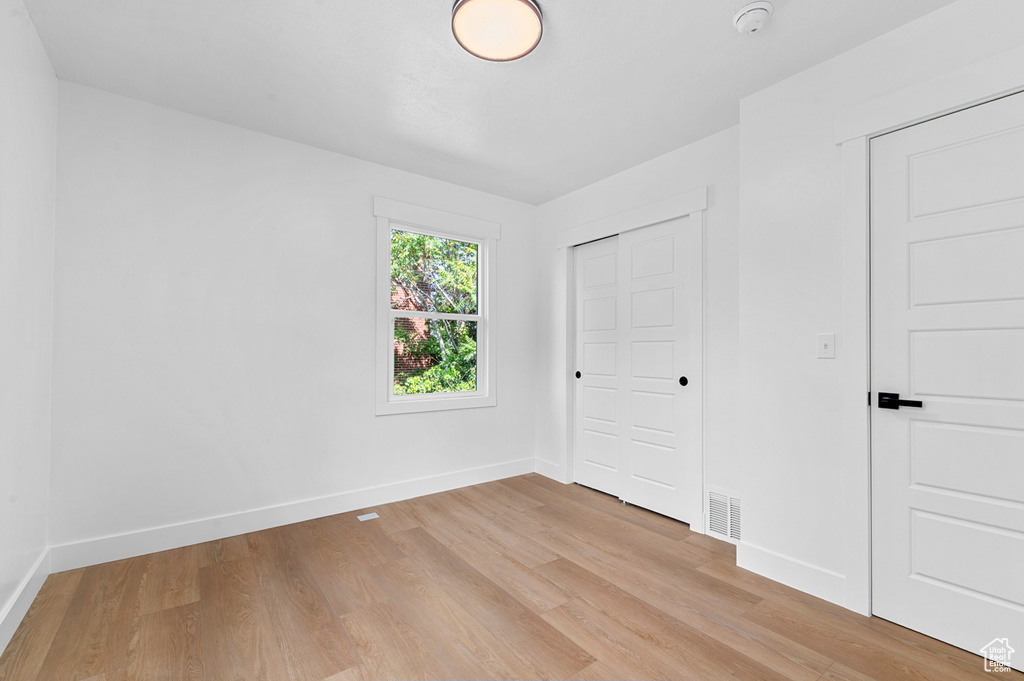 Unfurnished bedroom with light wood-style flooring, baseboards, and a closet