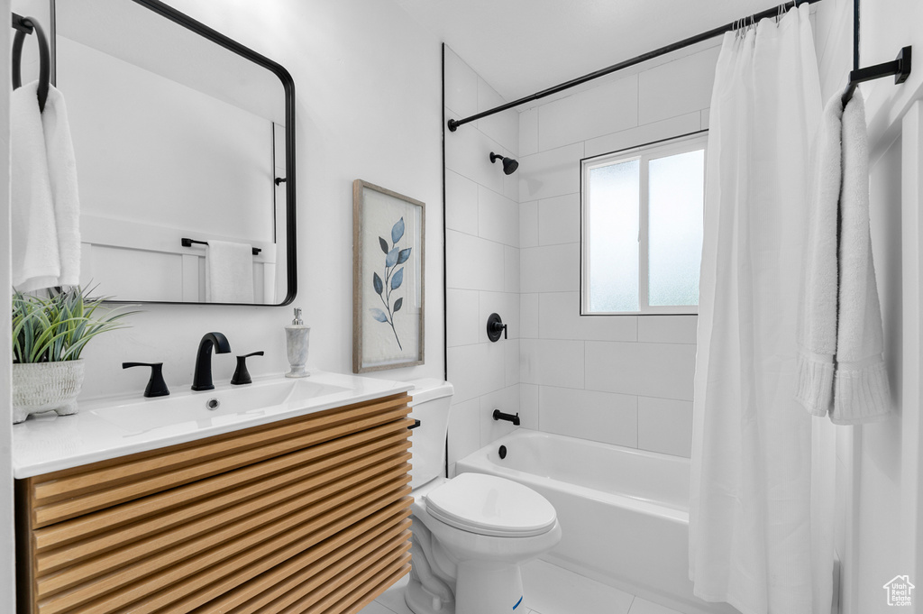 Bathroom featuring toilet, shower / tub combo with curtain, and vanity
