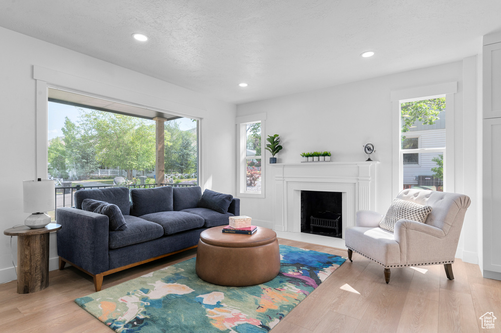 Living area featuring plenty of natural light, light wood finished floors, recessed lighting, a fireplace with flush hearth, and baseboards