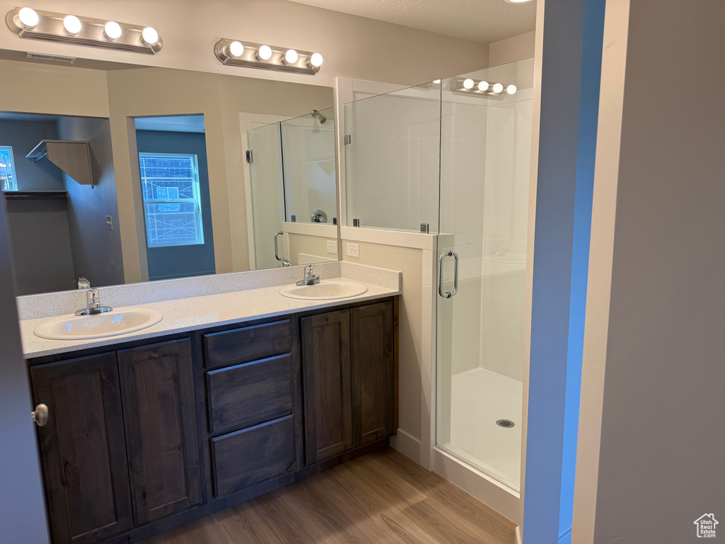 Bathroom with wood finished floors, a stall shower, and double vanity