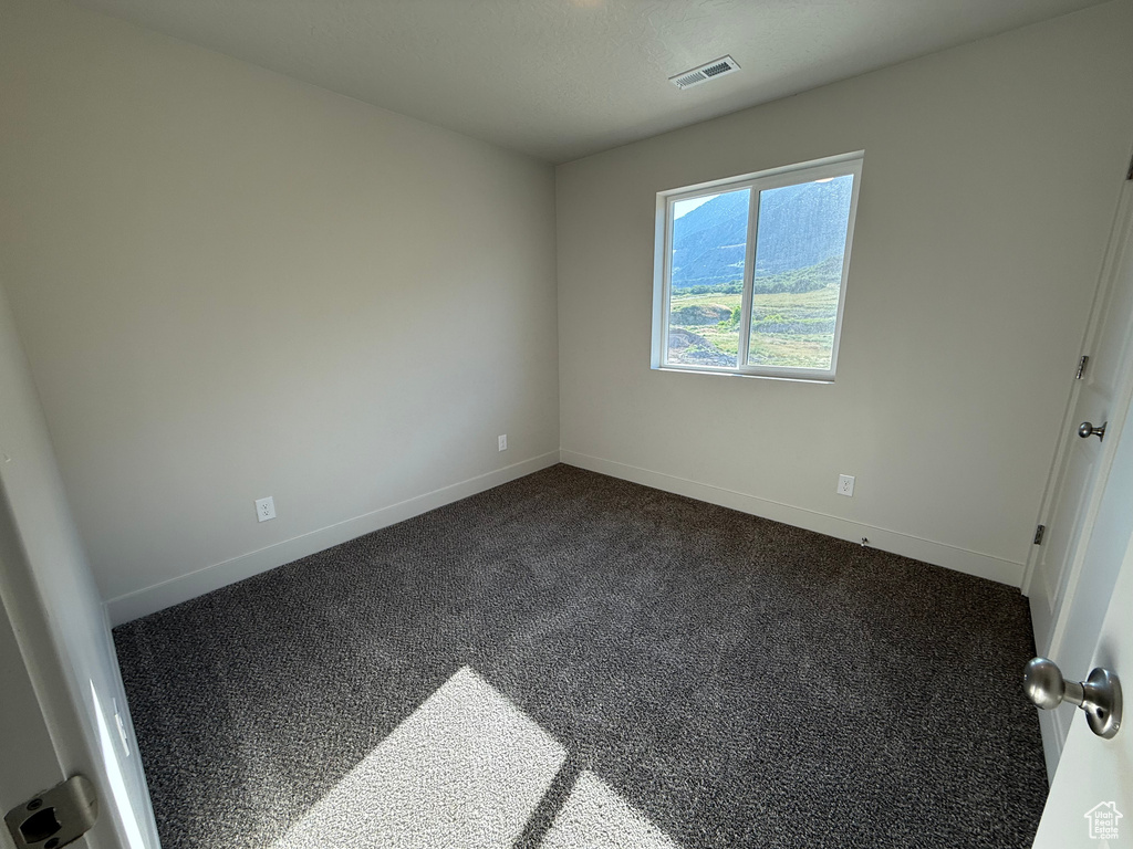Empty room featuring dark carpet and baseboards