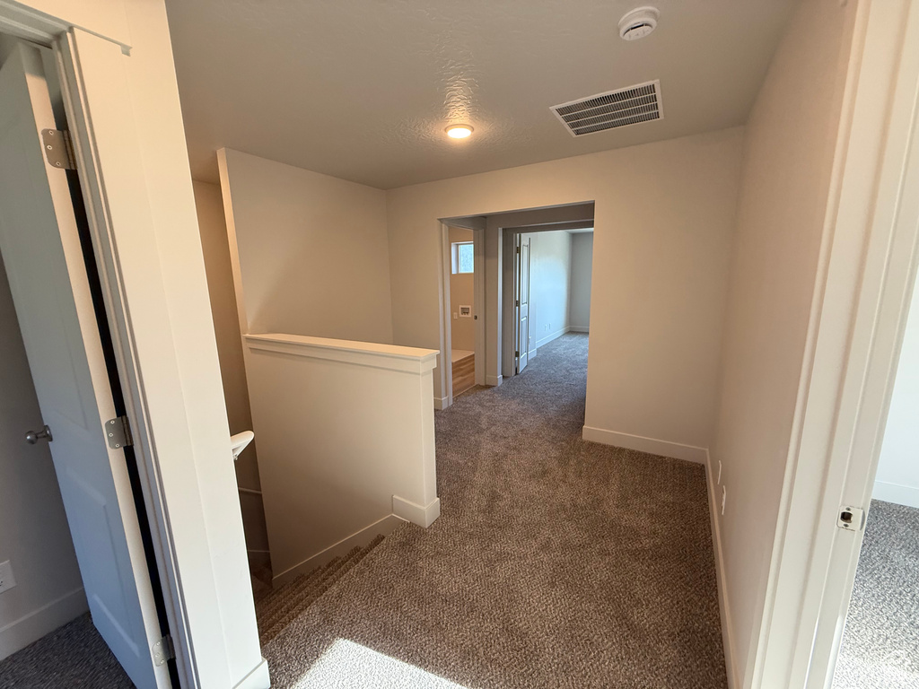 Corridor featuring an upstairs landing, carpet flooring, and baseboards