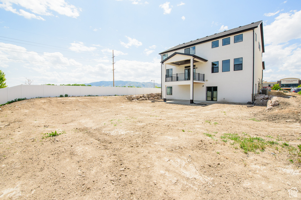 Rear view of property with a balcony, a mountain view, central AC, stucco siding, and a patio area