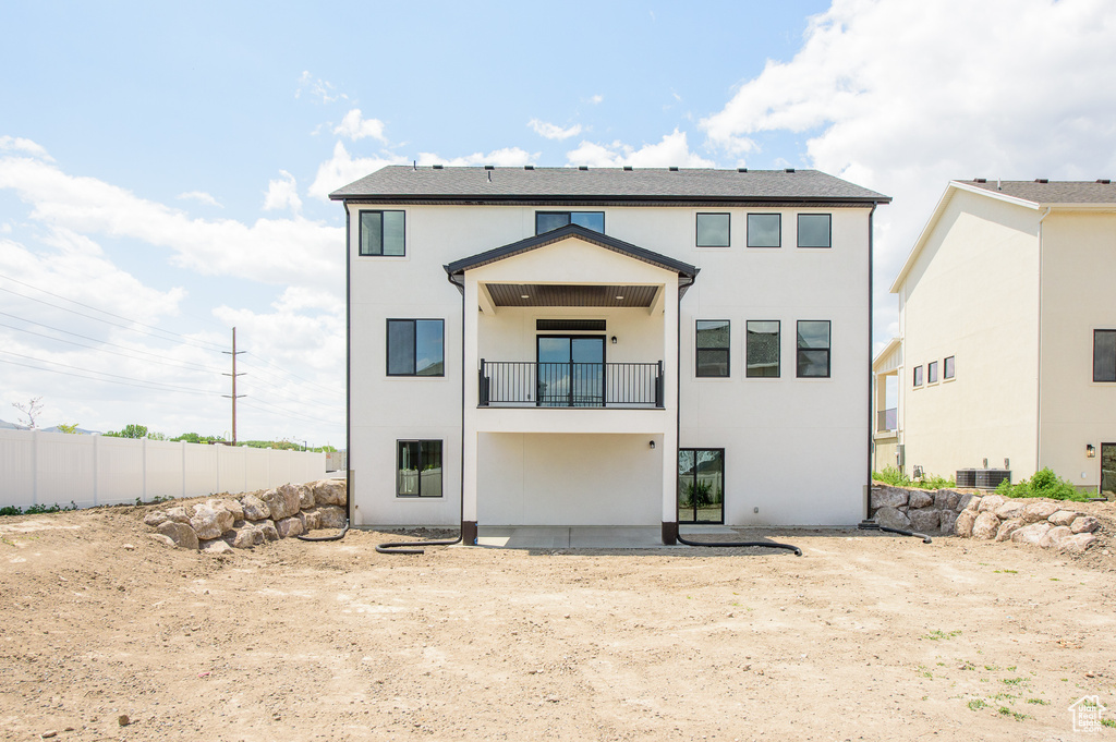 Back of property featuring a balcony, stucco siding, and central AC