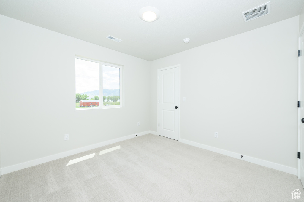 Spare room featuring light carpet and baseboards